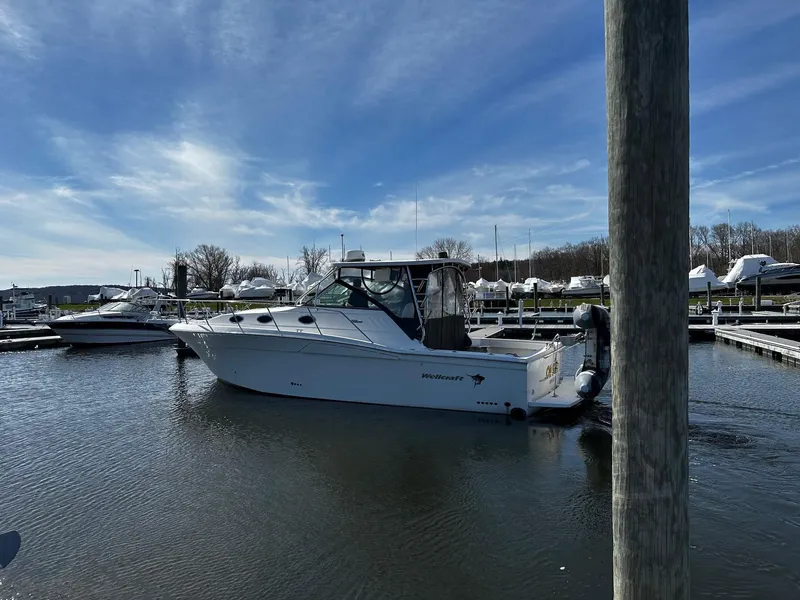 Slide: The Image of 2004 Wellcraft 330 Coastal boat docked in a marina under a clear blue sky. - 4