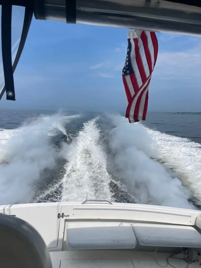 Slide: The Image of Wellcraft 330 Coastal boat cruising, American flag waving, ocean wake visible, clear blue sky. - 7