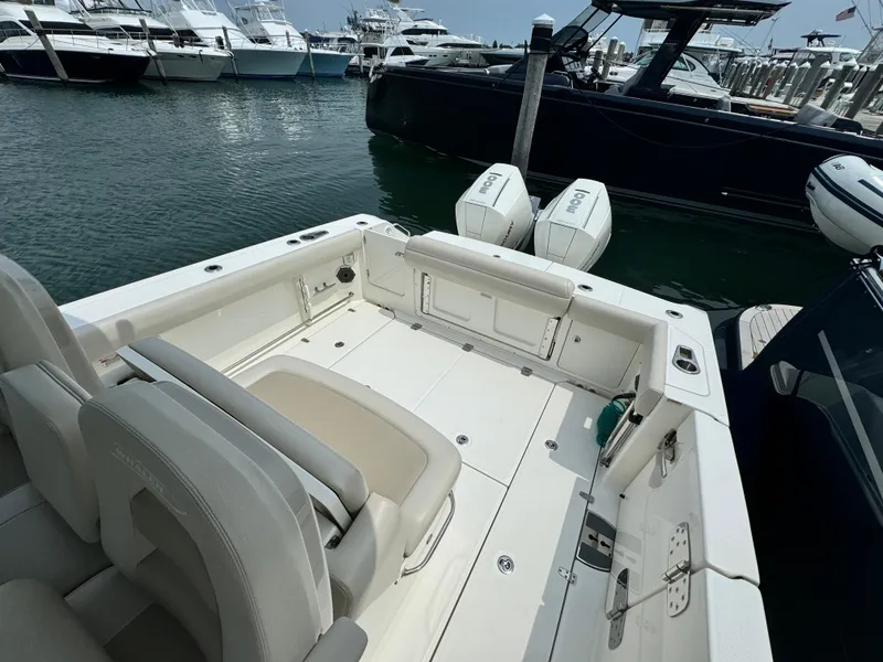 Slide: The Image of 2022 Boston Whaler 330 Outrage boat docked, featuring spacious deck and twin engines. - 10