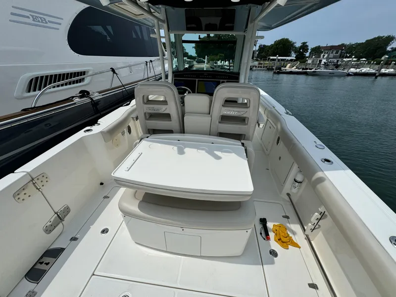 Slide: The Image of 2022 Boston Whaler 330 Outrage boat interior with seating and table, docked at marina. - 12