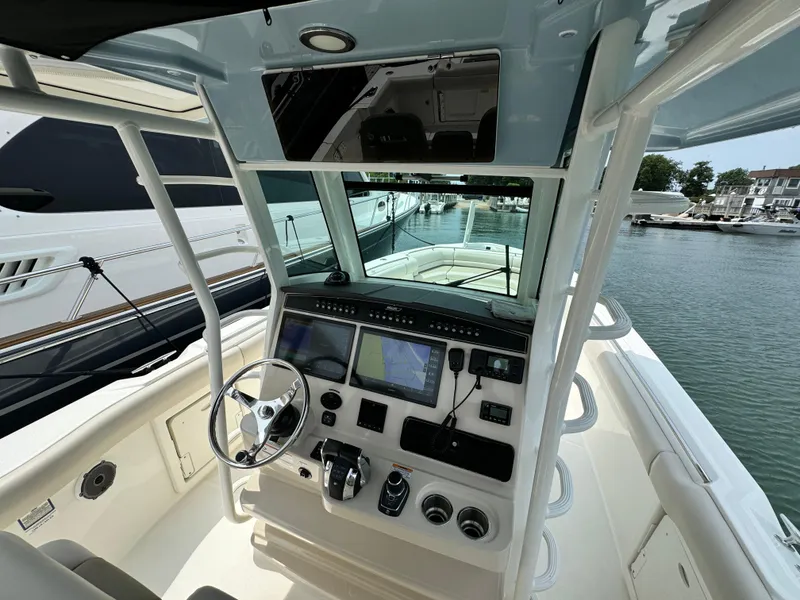 Slide: The Image of 2022 Boston Whaler 330 Outrage helm with advanced navigation systems, docked at marina. - 14