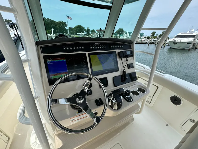 Slide: The Image of 2022 Boston Whaler 330 Outrage helm with advanced navigation system and steering wheel, docked at marina. - 15