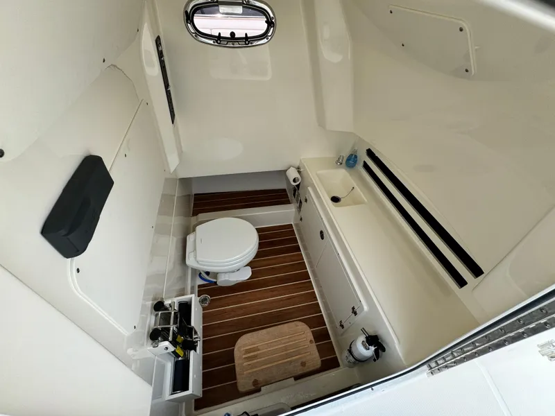 Slide: The Image of 2022 Boston Whaler 330 Outrage cabin interior with toilet and wooden flooring. - 17