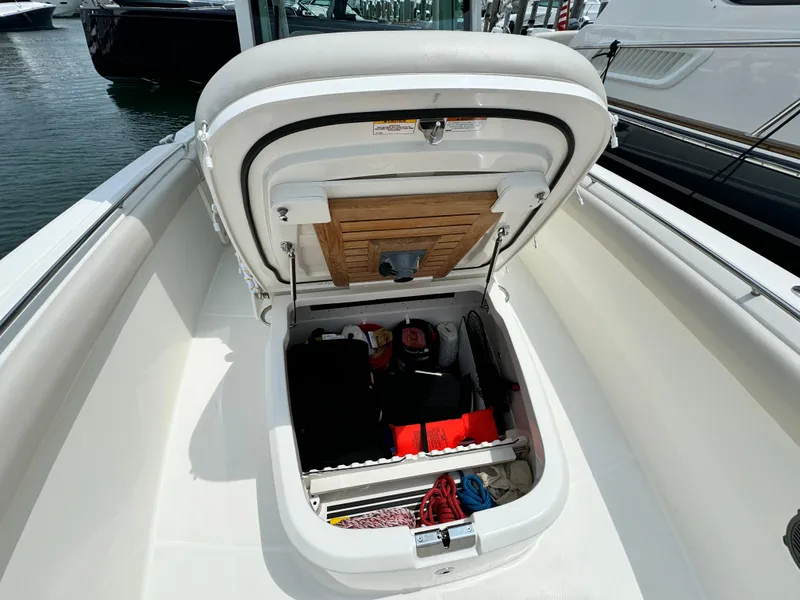 Slide: The Image of 2022 Boston Whaler 330 Outrage storage compartment open, revealing organized interior with boating essentials. - 21
