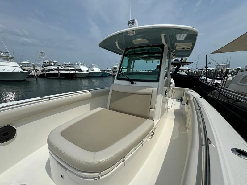 Slide: The Image of 2022 Boston Whaler 330 Outrage boat docked at marina, showcasing spacious seating and sleek design. - 22