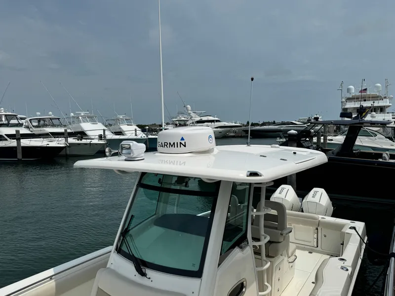 Slide: The Image of 2022 Boston Whaler 330 Outrage docked, featuring Garmin equipment, with other boats in the background. - 23