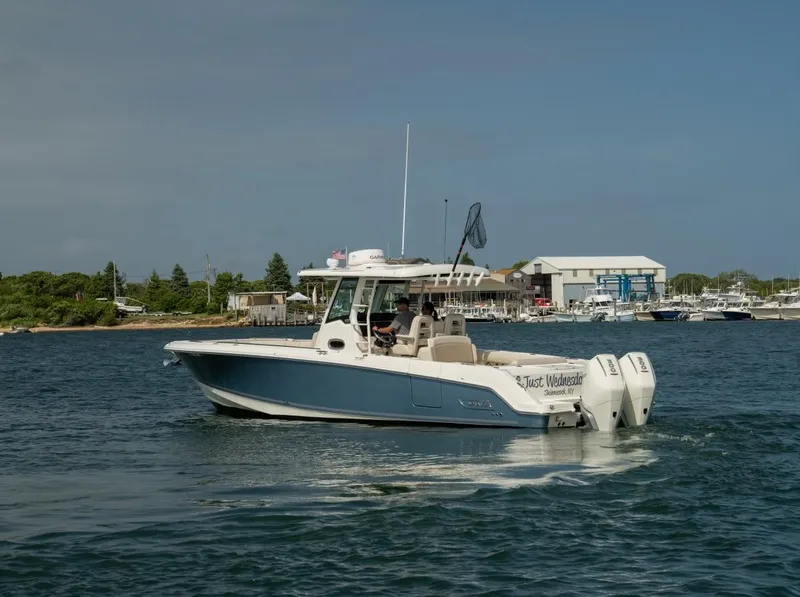 Slide: The Image of 2022 Boston Whaler 330 Outrage boat cruising on a calm waterway near a marina. - 3
