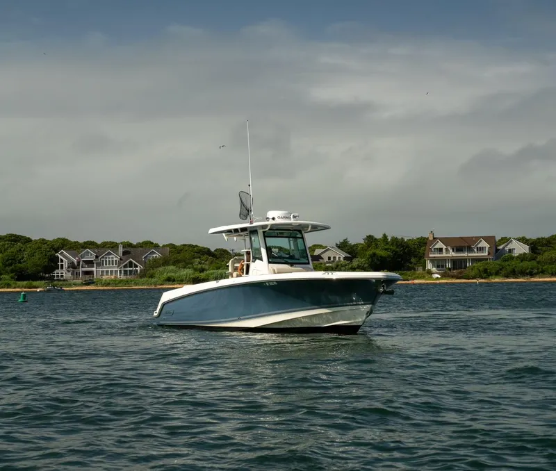 Slide: The Image of 2022 Boston Whaler 330 Outrage boat on water near coastal homes. - 5