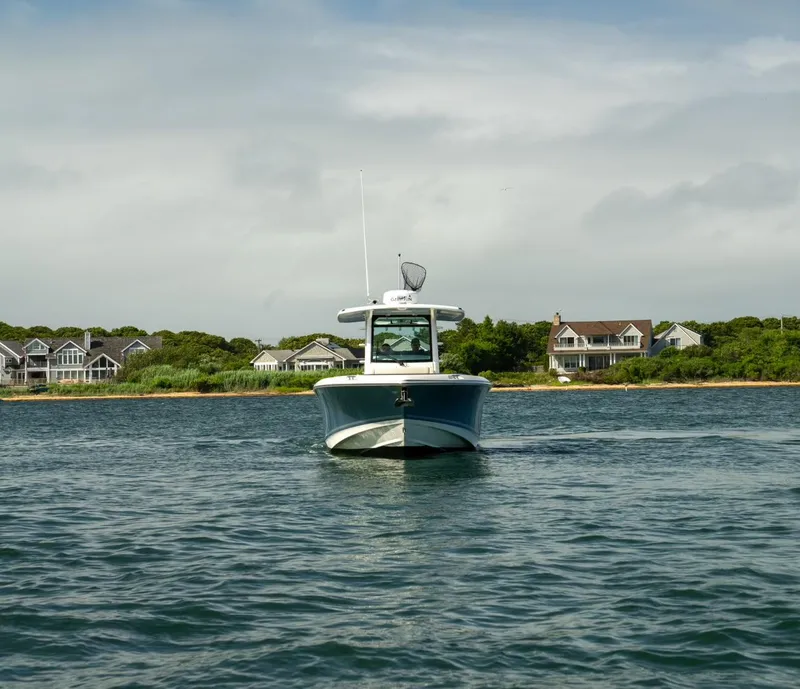 Slide: The Image of 2022 Boston Whaler 330 Outrage boat on water near coastal homes. - 6