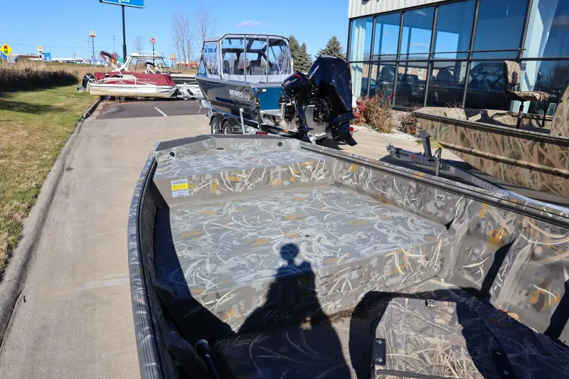 Slide: The Image of 2024 War Eagle 754LDV Sportsman boat with camouflage interior, parked outdoors. - 21