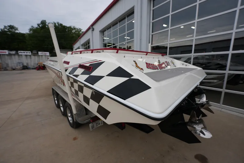 Slide: The Image of 1999 Fountain 35 Lightning speedboat with checkered flag design, parked outside a garage. - 8