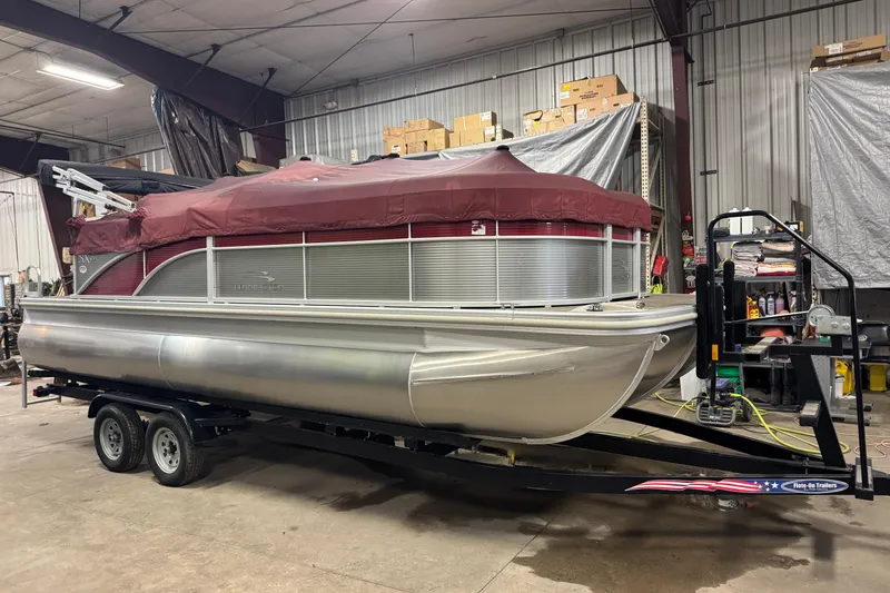 Slide: The Image of 2019 Bennington SX 21 Cruise pontoon boat with maroon cover on trailer in warehouse. - 34