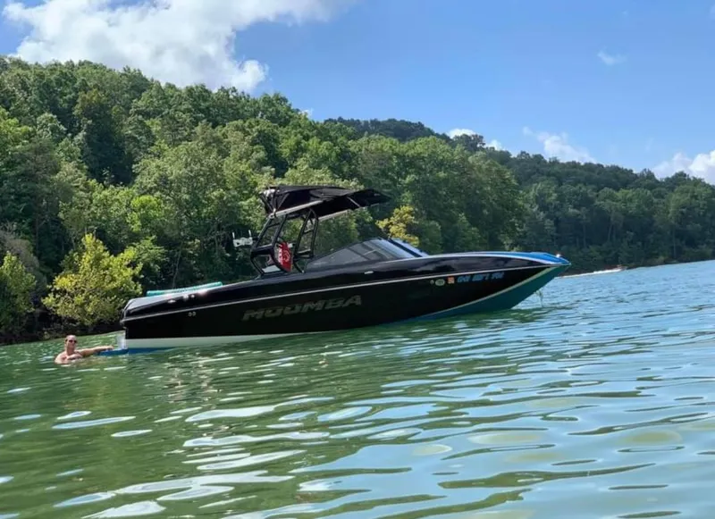 Slide: The Image of 2019 Moomba Craz boat on a lake with lush green forest background. - 2