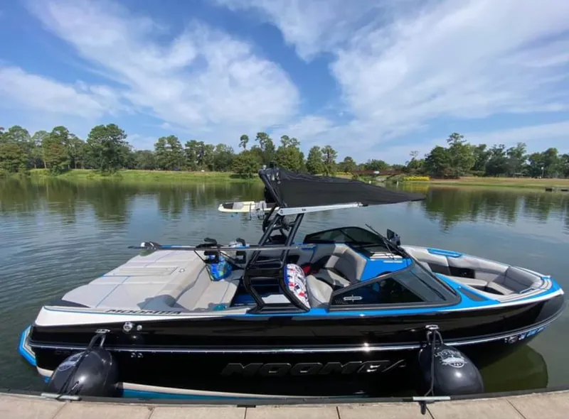 Slide: The Image of 2019 Moomba Craz boat docked on a calm lake with lush greenery. - 6