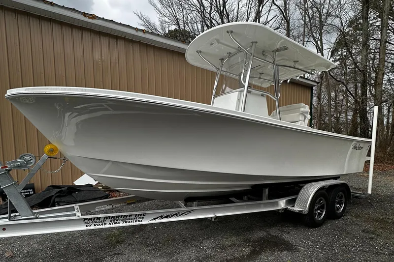 Slide: The Image of 2024 Pair Customs 21DV boat on trailer, parked outdoors near a brown building. - 9