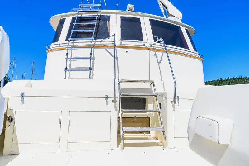 Slide: The Image of 1987 Hatteras 72 Flush Deck Cockpit Motor Yacht with ladder and windows under clear blue sky. - 10