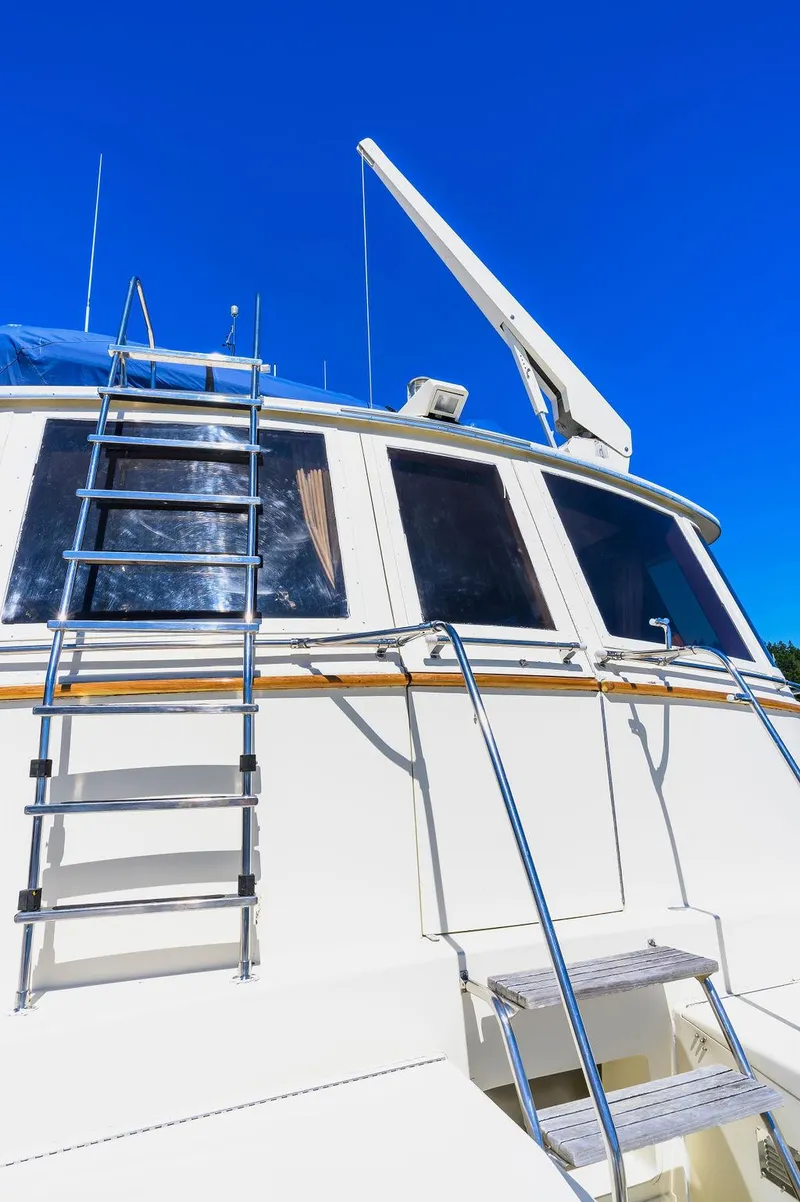 Slide: The Image of 1987 Hatteras 72 Flush Deck Cockpit Motor Yacht with ladder and windows under clear blue sky. - 13