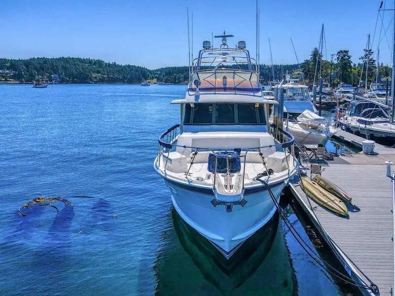 Slide: The Image of 1987 Hatteras 72 Flush Deck Cockpit Motor Yacht docked in a serene marina setting. - 2