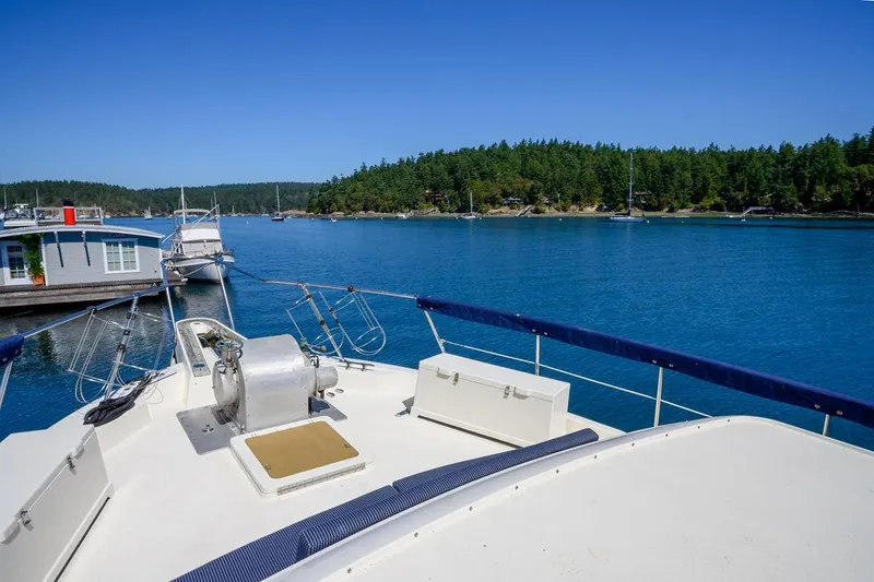 Slide: The Image of 1987 Hatteras 72 Flush Deck Cockpit Motor Yacht on serene blue water, forested shoreline. - 33