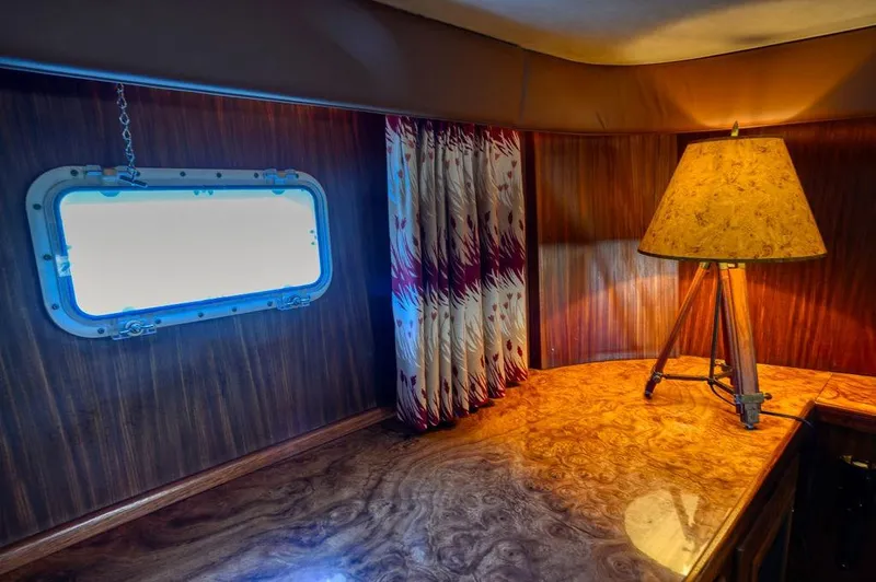 Slide: The Image of Interior of 1987 Hatteras 72 Yacht with wood paneling, lamp, and porthole window. - 41