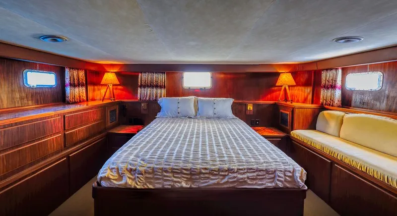 Slide: The Image of Luxurious bedroom in 1987 Hatteras 72 yacht with wood paneling and ambient lighting. - 42