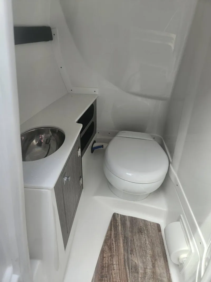 Slide: The Image of 2022 Monterey 278SS boat bathroom with toilet, sink, and wooden flooring. - 9