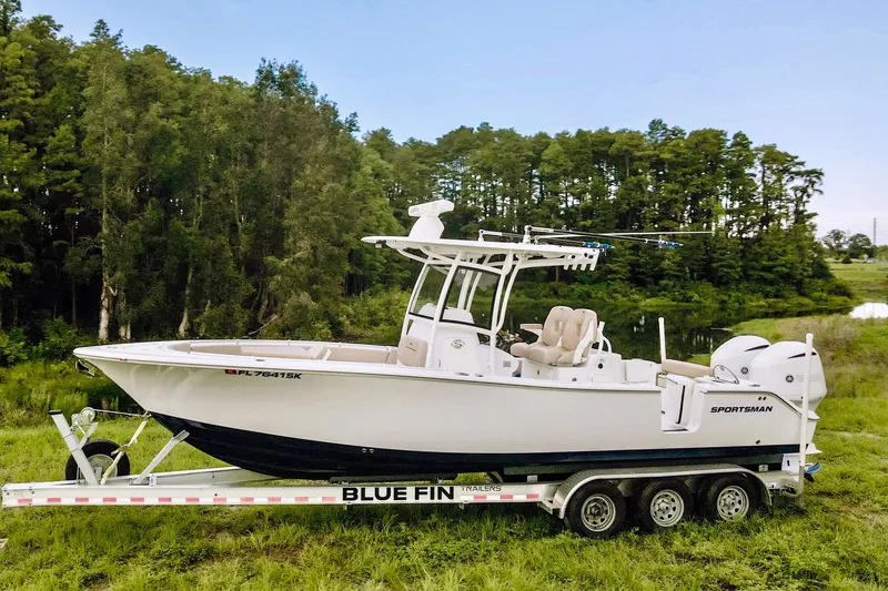 Slide: The Image of 2019 Sportsman Open 282 Center Console boat on Blue Fin trailer in grassy area. - 4