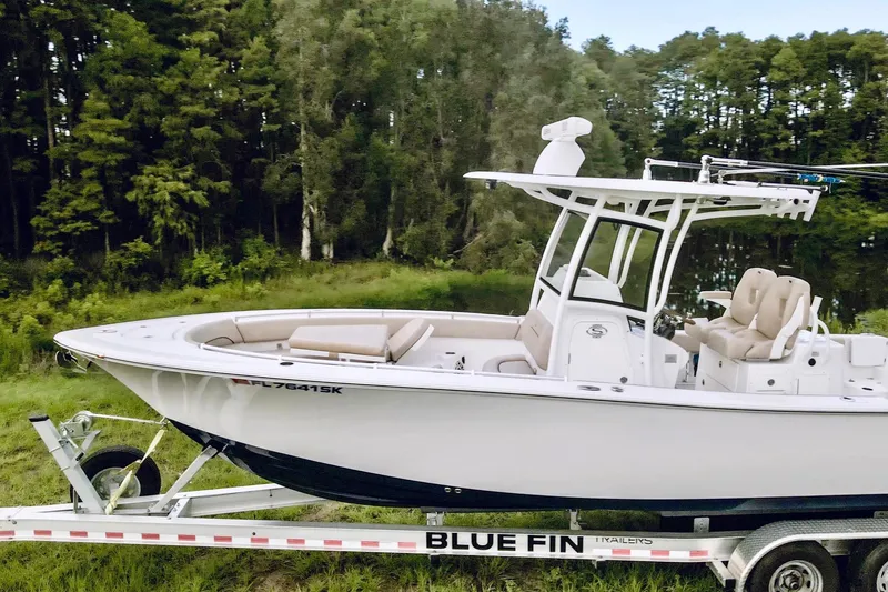 Slide: The Image of 2019 Sportsman Open 282 Center Console boat on Blue Fin trailer in a forested area. - 5