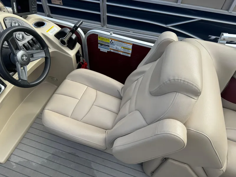 Slide: The Image of Captain's seat and steering wheel of 2016 Godfrey Sweet Water boat, featuring beige upholstery. - 19
