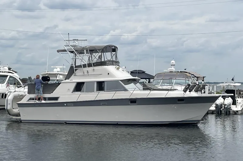 The Image of 1987 Silverton 40 Double Cabin yacht docked in a marina under cloudy skies. - 0