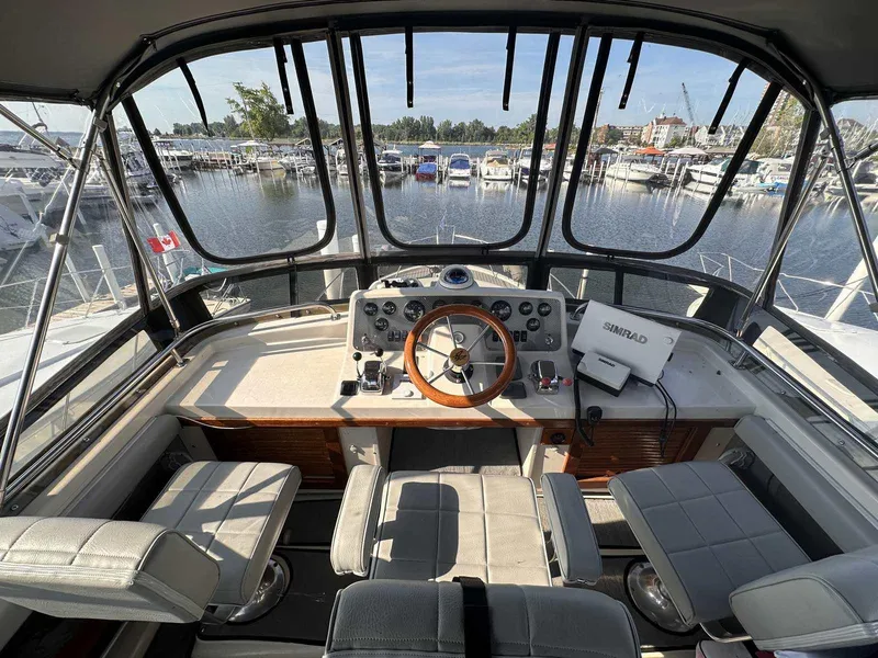 Slide: The Image of 1987 Silverton 40 Double Cabin helm with panoramic marina view, featuring classic controls and seating. - 17