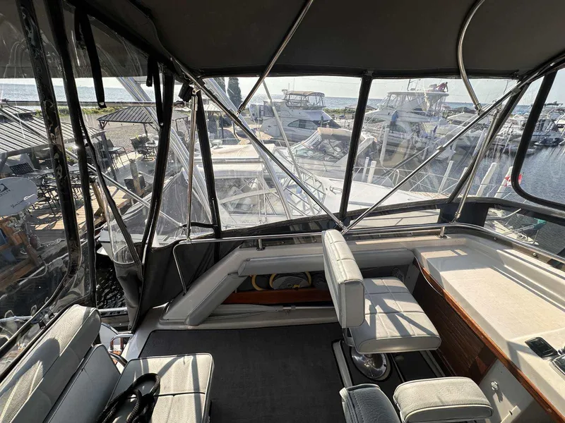 Slide: The Image of 1987 Silverton 40 Double Cabin interior with marina view, featuring seating and helm area. - 19