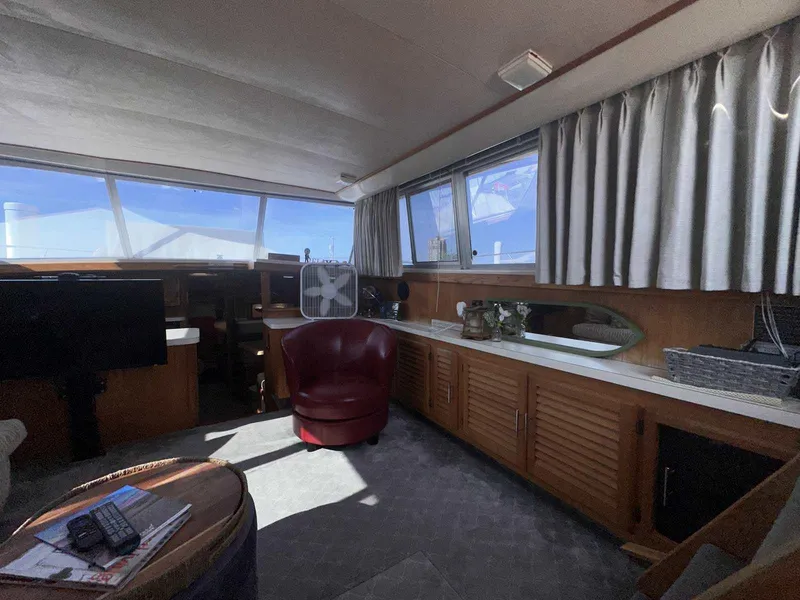 Slide: The Image of 1987 Silverton 40 Double Cabin interior with red chair, windows, and wooden cabinetry. - 48