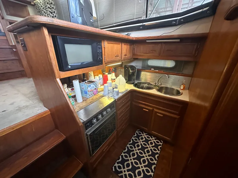 Slide: The Image of 1989 Carver 3807 Aft Cabin kitchen with wood cabinetry, microwave, and dual sinks. - 22