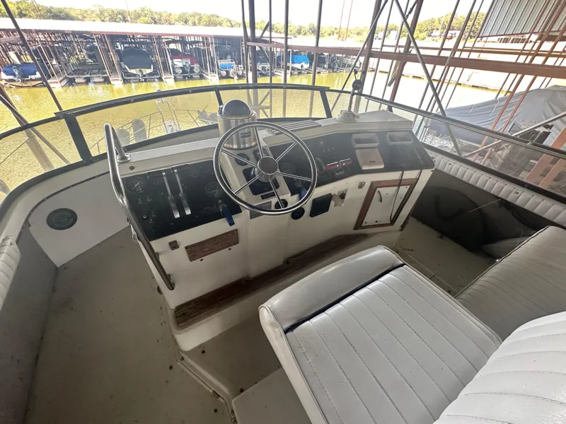 Slide: The Image of 1989 Carver 3807 Aft Cabin helm with steering wheel and controls, docked in marina. - 8