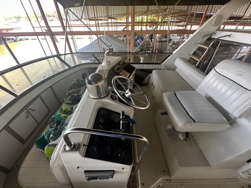 Slide: The Image of 1989 Carver 3807 Aft Cabin yacht helm with white seating and steering wheel. - 12
