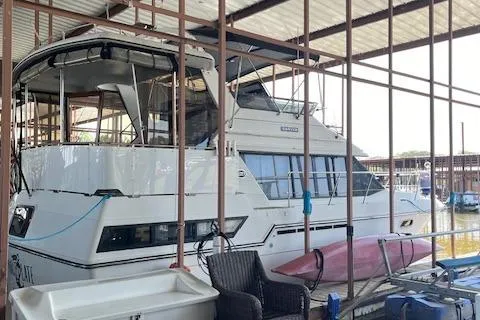 Slide: The Image of 1989 Carver 3807 Aft Cabin yacht docked in a marina with kayaks and outdoor furniture. - 2