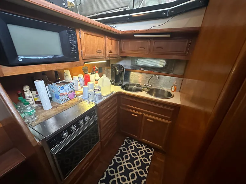 Slide: The Image of 1989 Carver 3807 Aft Cabin kitchen with microwave, stove, and dual sinks. - 23