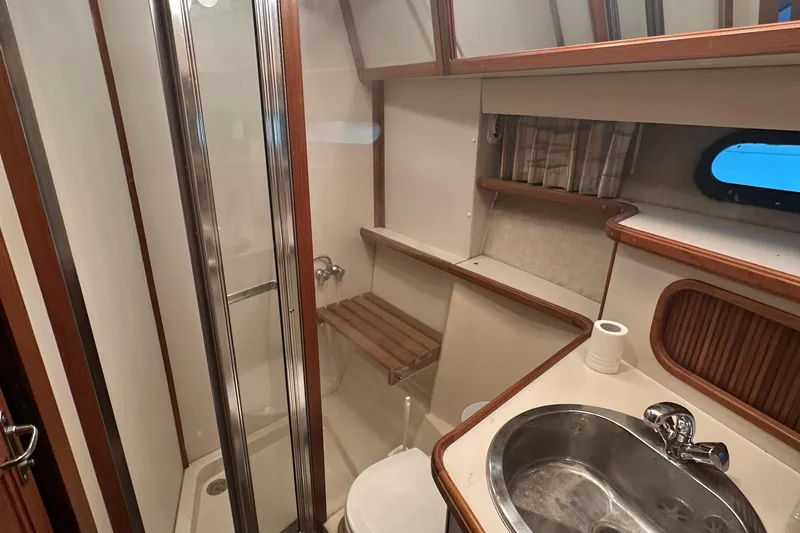 Slide: The Image of 1989 Carver 3807 Aft Cabin bathroom with shower, sink, and wooden accents. - 26