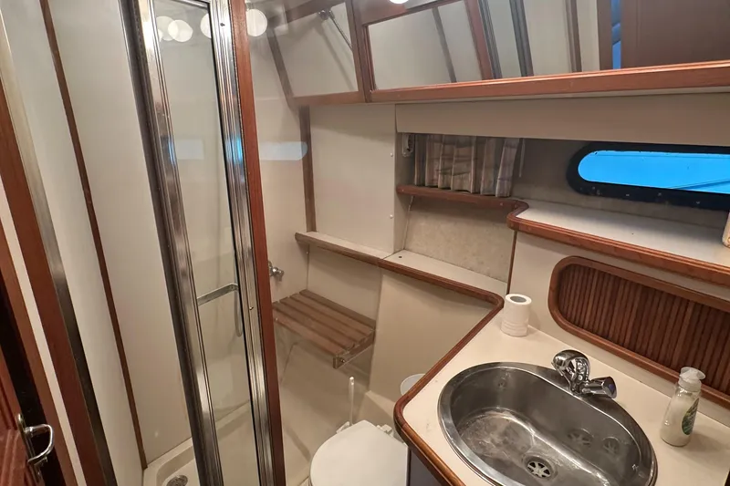 Slide: The Image of 1989 Carver 3807 Aft Cabin bathroom with sink, shower, and wooden accents. - 27