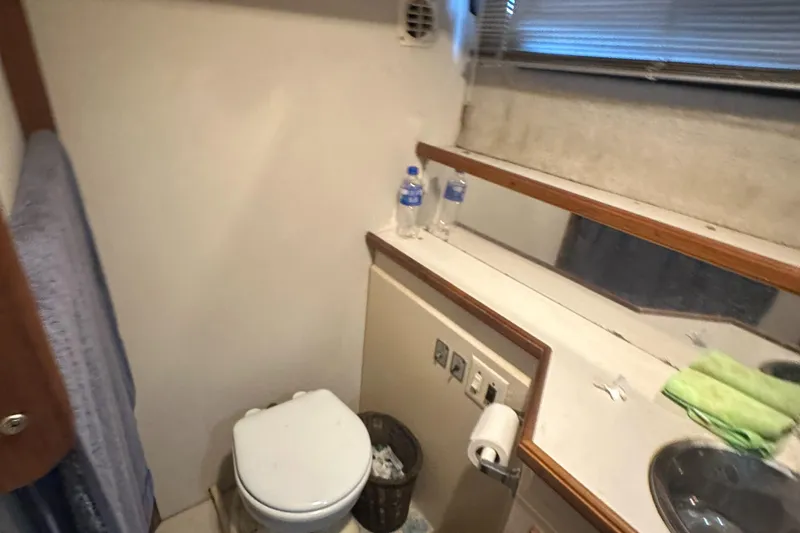 Slide: The Image of 1989 Carver 3807 Aft Cabin bathroom with toilet, sink, and mirror. - 34