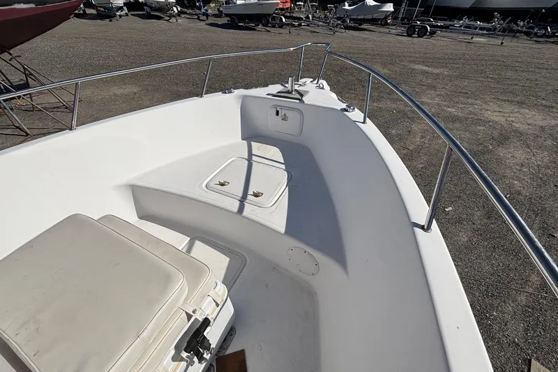 Slide: The Image of 2004 Pro-Line 20 Sport boat deck with seating and storage, parked on gravel. - 5