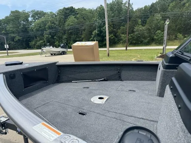 Slide: The Image of 2024 Lund 1875 Impact XS Sport boat interior with gray carpet and storage compartments. - 10