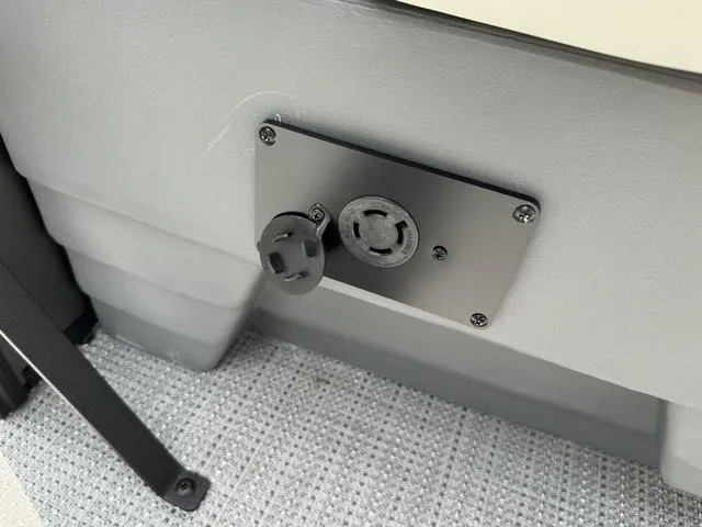 Slide: The Image of 2024 Starcraft EXS 3 HB4 boat electrical outlet and plug on gray panel. - 27