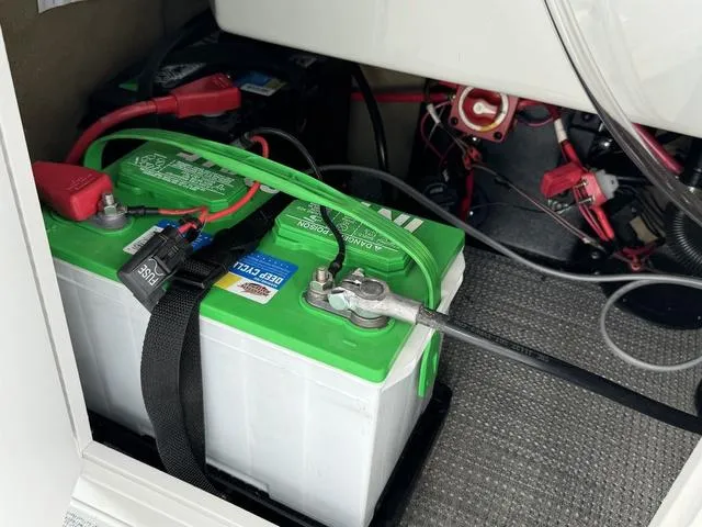 Slide: The Image of 2024 Starcraft EXS 3 HB4 boat battery compartment with green and white battery. - 31