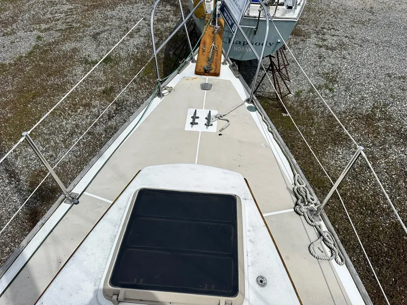 Slide: The Image of 1982 Cape Dory 30 sailboat deck with hatch and railing, on gravel surface. - 15