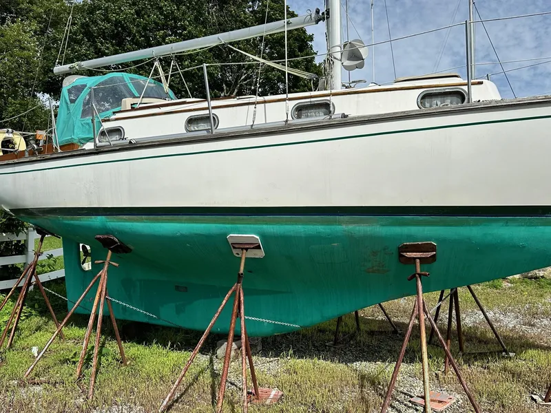 Slide: The Image of 1982 Cape Dory 30 sailboat on stands, white and teal hull, outdoor setting. - 4