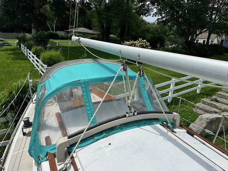 Slide: The Image of 1982 Cape Dory 30 sailboat with teal canopy, docked near lush greenery and white fence. - 8