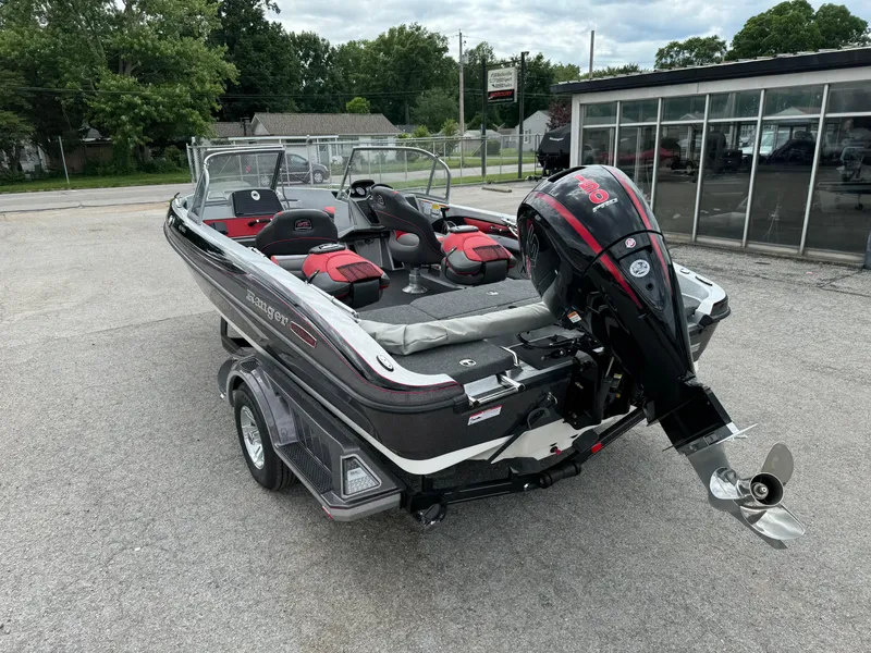 Slide: The Image of 2024 Ranger 1850MS boat with outboard motor, parked outdoors near a glass building. - 6