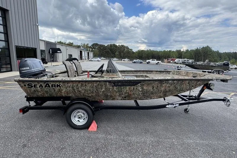 Slide: The Image of 2025 SeaArk Shadow 17 Side Console boat on trailer, camo design, parked outdoors. - 19